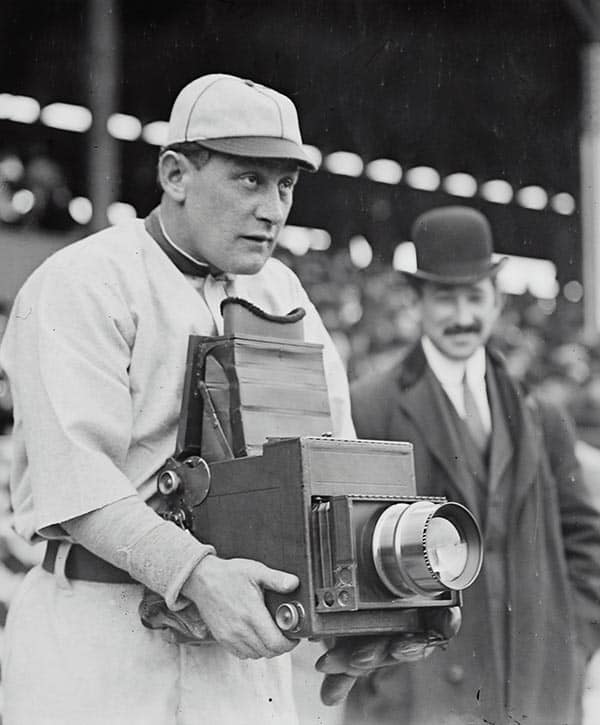 an old photo of a baseball player holding a camera.